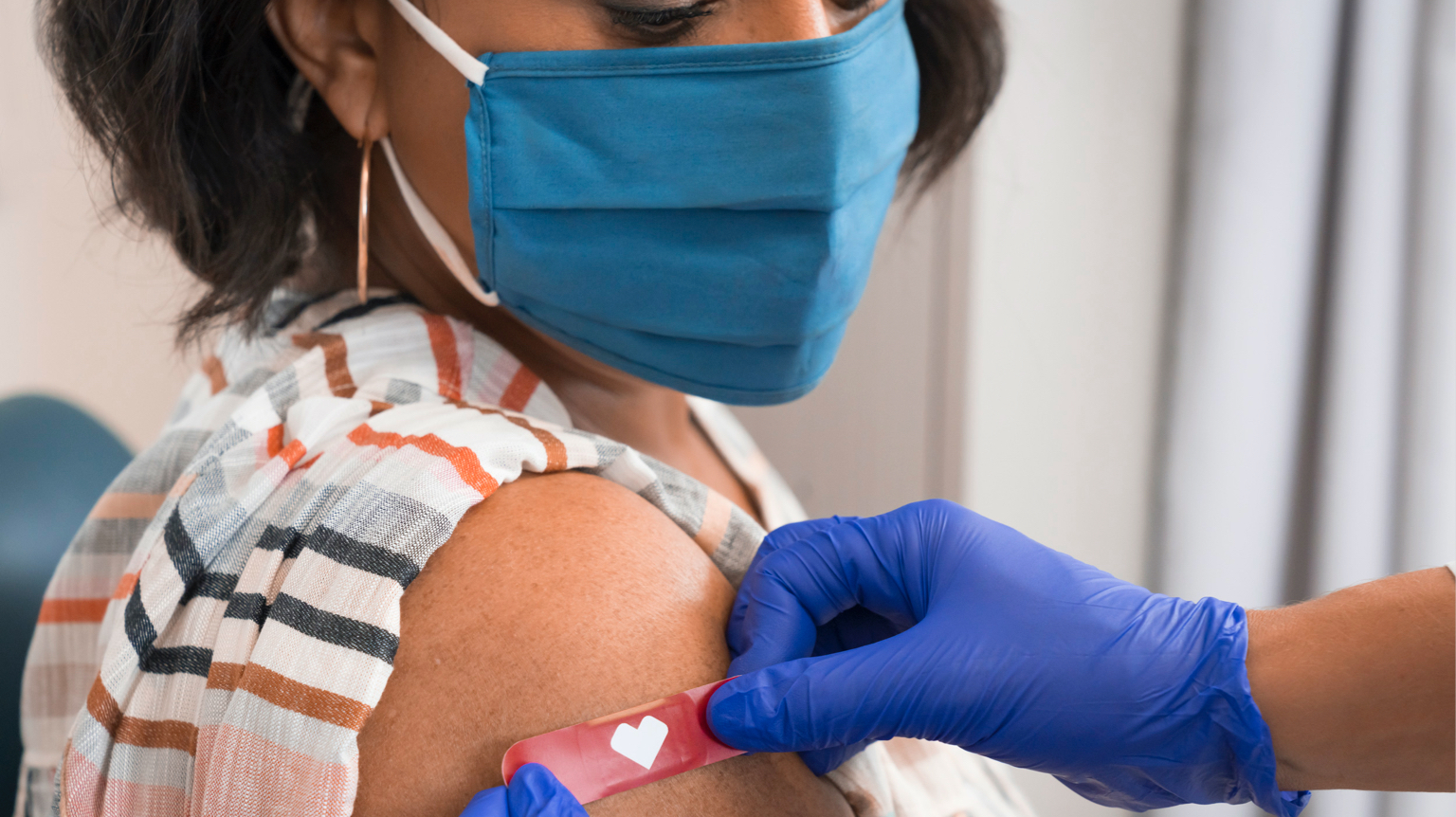 Photograph of a female patient having a CVS bandage applied after receiving vaccine.